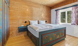 Das Bild zeigt ein Schlafzimmer des Ferienhaus Eixer am Bödele. Das Schlafzimmer ist mit einem Doppelbett und einem großen Wandschrank ausgestattet.